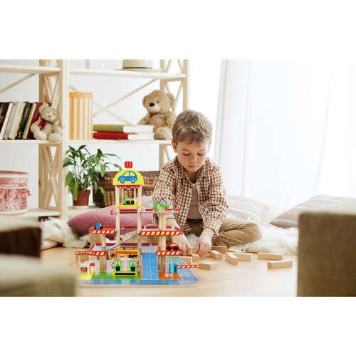Little child sitting on the floor. Pretty boy palying with wooden cubes at home Didelis medinis garažas su priedais